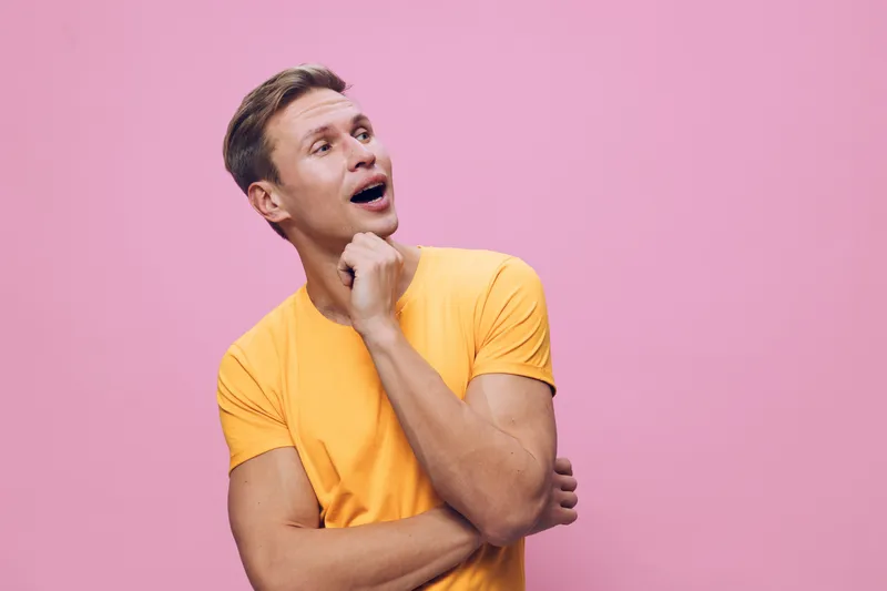 Young thoughtful caucasian man in yellow t-shirt look away isolated on pink background studio portrait digital detox concept