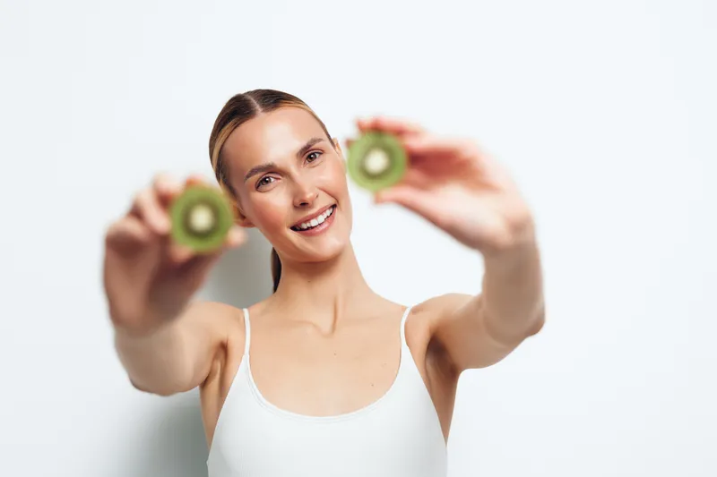 Smiling woman lifting green dumbbells in a bright studio, strength training exercise workout for fitness and wellness, focused posture, soft studio lighting, health concept
