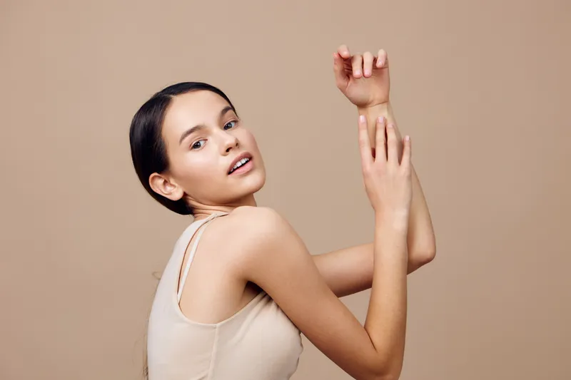 Young woman with smooth skin posing gracefully against a warm beige background, expressing confidence Perfect for beauty, skincare, and fashion concepts