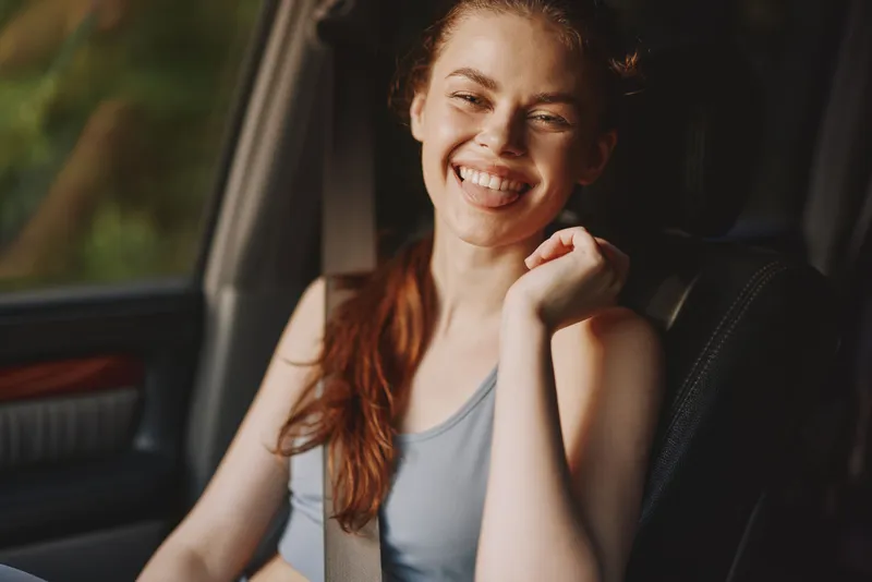 Smiling young woman in sportswear sitting in a car, radiating happiness and confidence, perfect for healthy lifestyle concepts and fitness promotions