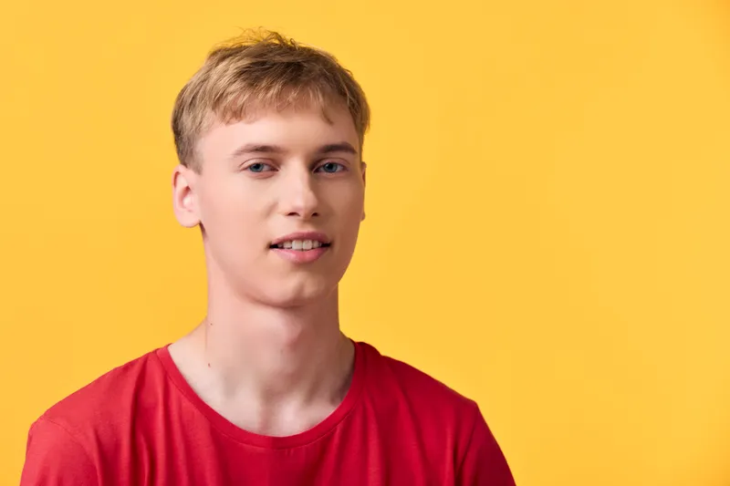 Man wearing a red t shirt against a bright yellow background, studio lighting, casual style, close up, confident expression, clean lifestyle vibe suitable for stock, fashion or advertising imagery