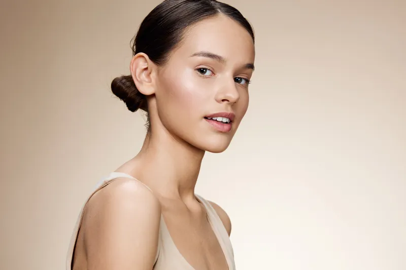 Natural beauty portrait of a young woman with a serene expression, featuring soft, neutral tones and smooth skin, perfect for wellness and skincare concepts