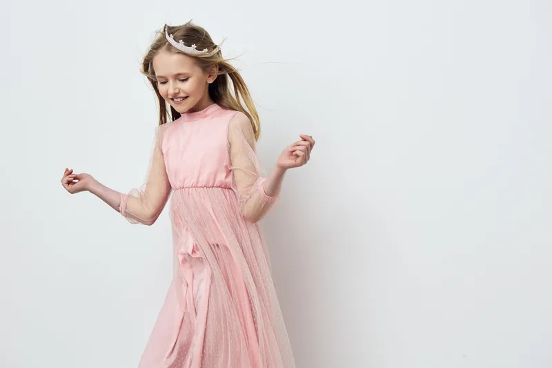 Joyful young girl in a pink tulle dress dancing against a light backdrop, capturing the essence of childhood happiness and carefree moments