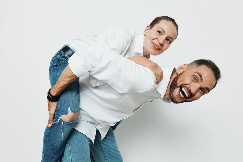 A professional man and colleague share a playful moment against an isolated blue background, conveying confidence, teamwork, and approachable demeanor ideal for business and corporate communications.