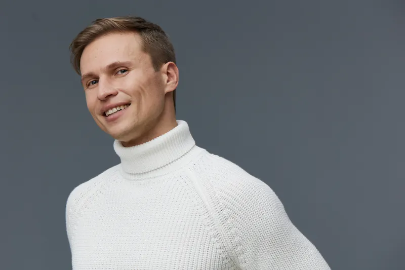 Smiling man wearing white turtleneck sweater look camera portrait isolated grey background concept digital nomad remote work lifestyle