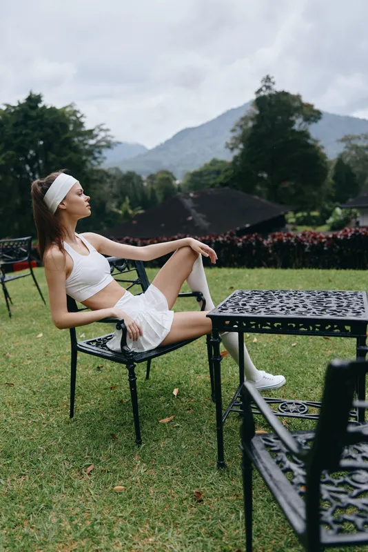 Stylish young woman in athletic wear, enjoying outdoors on a summer day, showcasing healthy lifestyle and relaxation amidst greenery