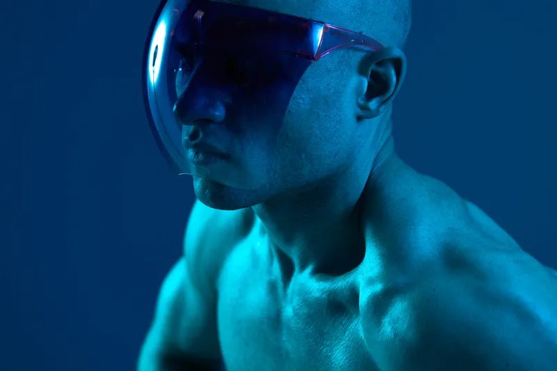 Strong man wearing futuristic visor in a captivating blue light setting. The image showcases an abstract aesthetic, evoking modernity and intrigue.