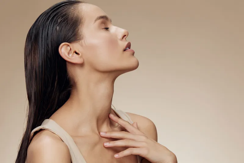 Elegant profile of a female model with long hair, showcasing natural beauty and grace against a soft beige background, highlighting serenity and sophistication