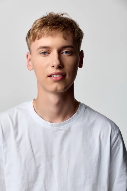 Young man wearing a white tshirt for a casual headshot in a studio with a neutral background, relaxed expression and soft lighting, ideal for lifestyle, fashion or modeling projects