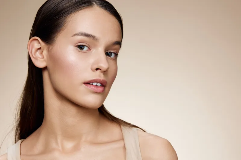 Portrait of a young woman with natural makeup and neutral background, reflecting beauty, elegance, and tranquility in a minimalist style