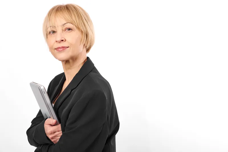 Business woman senior clipboard manager corporate portrait white background, black suit, holds clipboard with calm confident smile, studio isolation, copy space.