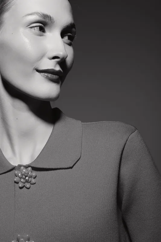 Portrait of a fair skinned Caucasian woman smiling softly in vintage style with soft lighting on dark background.