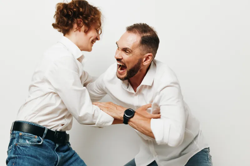 A business professional man and colleague share a bold moment against an isolated white background, showcasing determination, energy, and teamwork in a candid, expressive pose.