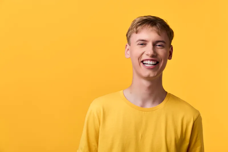 Smiling man in a yellow shirt against a vibrant yellow backdrop, showcasing warmth, energy and approachable style for lifestyle, advertising or marketing scenes