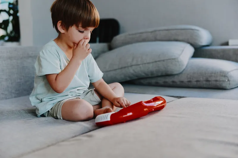 Curious boy playing with toy piano in a cozy living room, engaging with music. Bright and playful atmosphere enhances creativity and imagination.