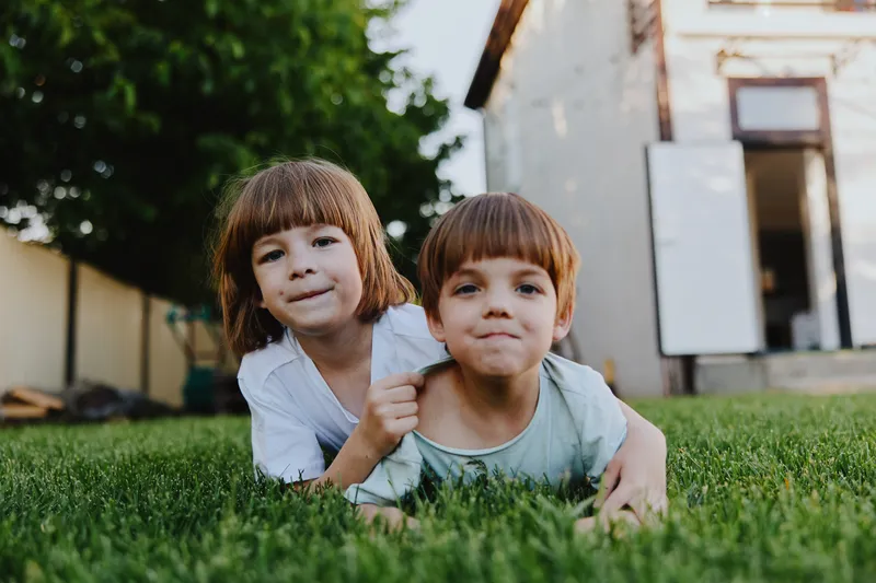 Two joyful children playing together outdoors on a sunny day, one girl and one boy, showcasing happiness and innocence in a natural setting.