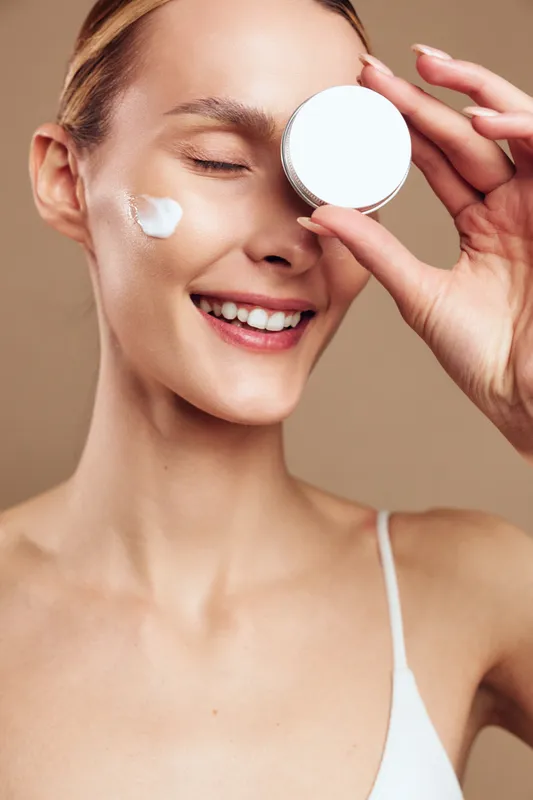 Smiling woman applying eye cream with a cotton pad, closeup on face, skincare treatment, hygiene and hydration concept, daily beauty routine, calm relaxation