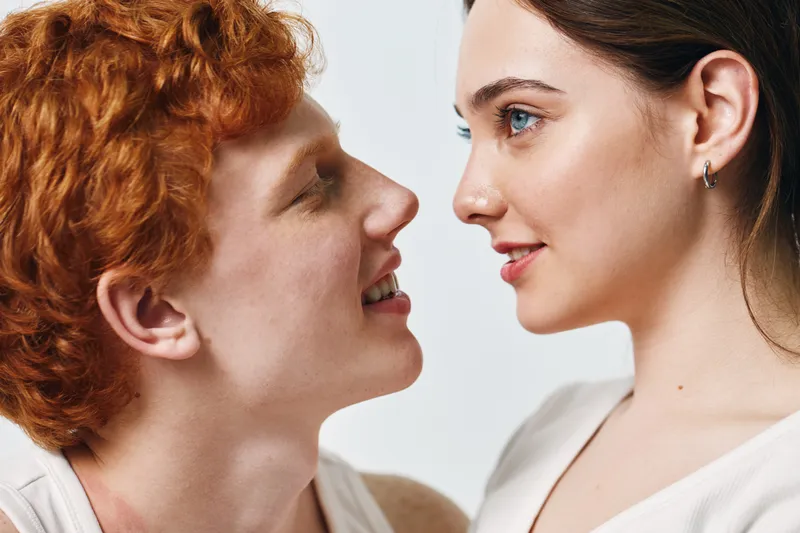Man and woman facing each other with close intimacy, smiling and looking into each other eyes, relationship, love and connection between two people in studio light.