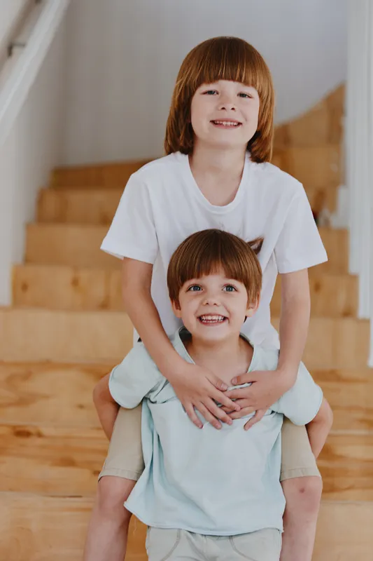 Two cheerful boys playing on wooden stairs, showcasing their joy and strong bond. This charming scene perfectly captures childhood happiness.