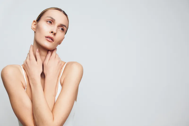 Woman portrait, skincare beauty and calm studio hands on neck, natural complexion, relaxed gaze, soft lighting, minimal background, copy space for beauty concept, healthy skin texture