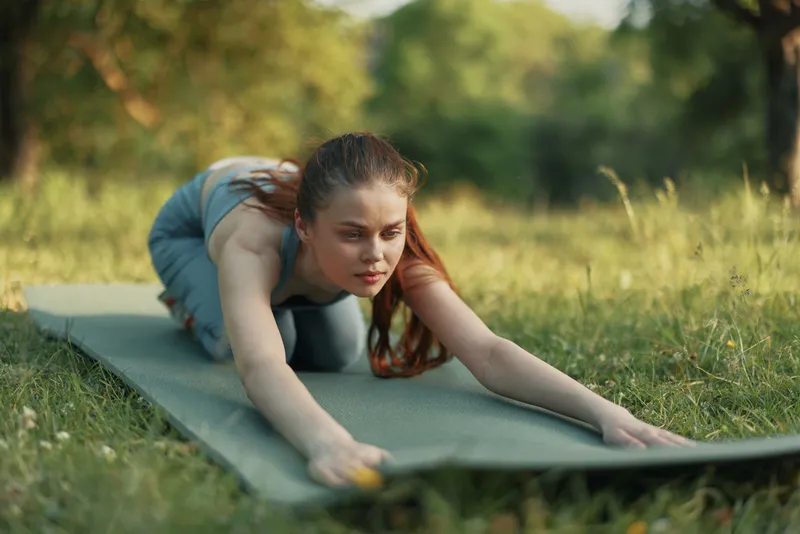 Young woman practicing yoga in a serene outdoor setting, focusing on mindfulness and flexibility, embodying tranquility and health in nature
