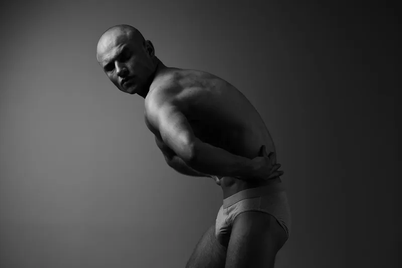 Black and white portrait of a man showcasing strong physique and emotional depth, creating a captivating atmosphere that evokes strength and vulnerability.
