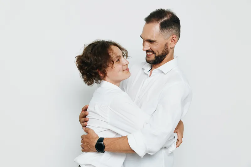 A professional male business figure shares a warm moment with a colleague against an isolated colored background, showcasing confidence, emotion and teamwork in a studio setting.