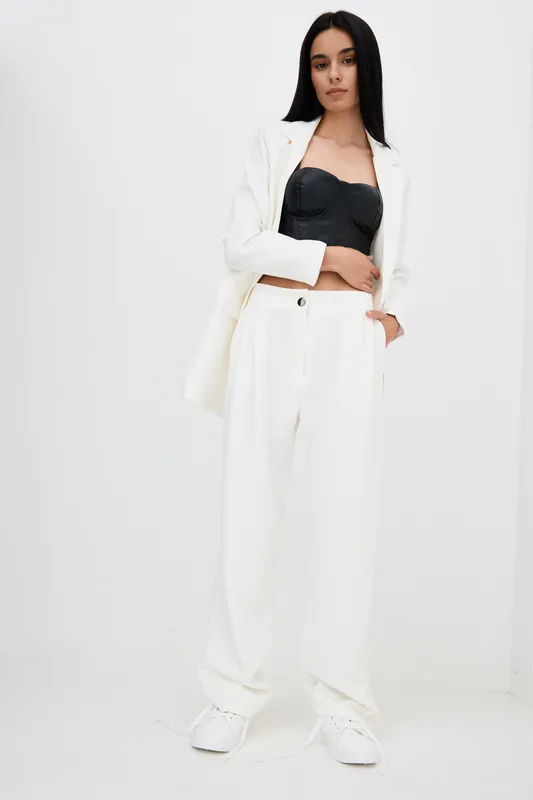 woman in white wide pants and black corset top posing in minimalist studio with white background, modern fashion style and casual attitude