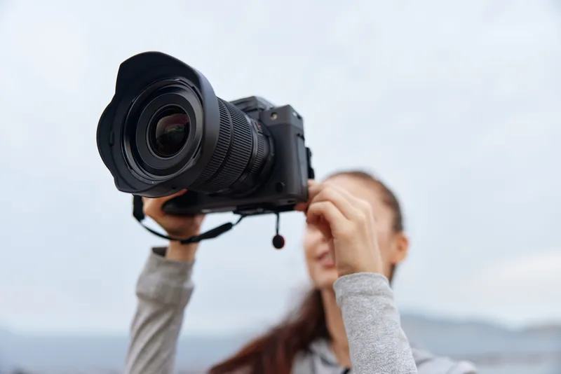 A young woman capturing stunning outdoor moments with a professional camera, showcasing her passion for photography in a serene natural setting