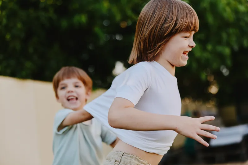 Playful children running outdoors, enjoying a sunny day with happiness and laughter, representing friendship and childhood joy in vibrant colors.