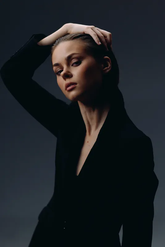 Portrait of a serious woman with braided hair in a black jacket against dark background