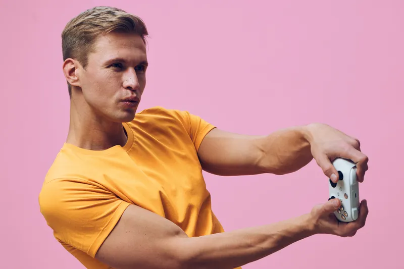 young man focused play video games hold joystick pink background casual outfit digital entertainment concept