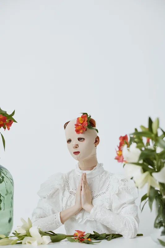 A serene and artistic portrait of a model in a white ruffled dress, adorned with flowers, creating a peaceful atmosphere focused on tranquility and beauty
