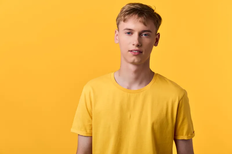Yellow shirt and calm man in a studio setting with bright backdrop, casual wear, fashion vibe, clean lighting and minimal background for lifestyle or apparel use.