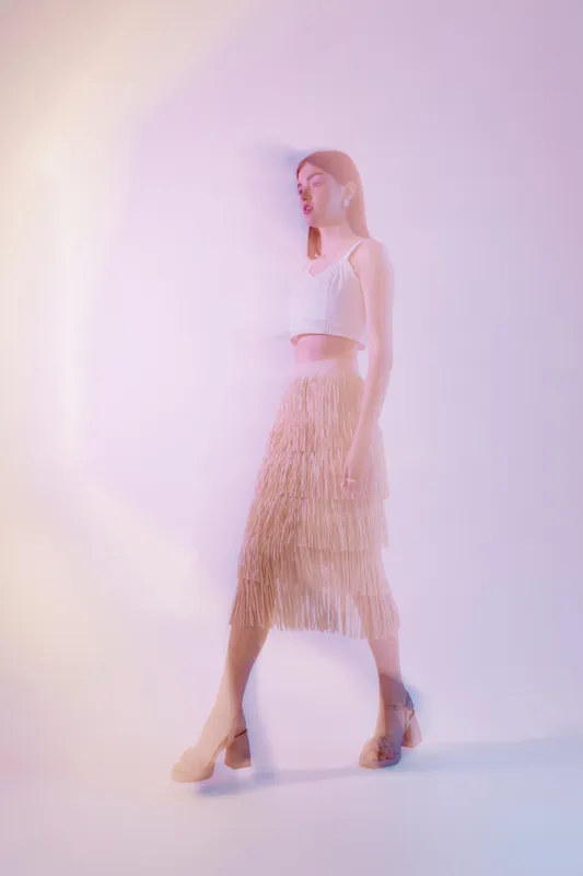 Young woman in stylish fashion outfit poses against soft pastel background. Concept of beauty, style, elegance, and modern female fashion in studio lighting.