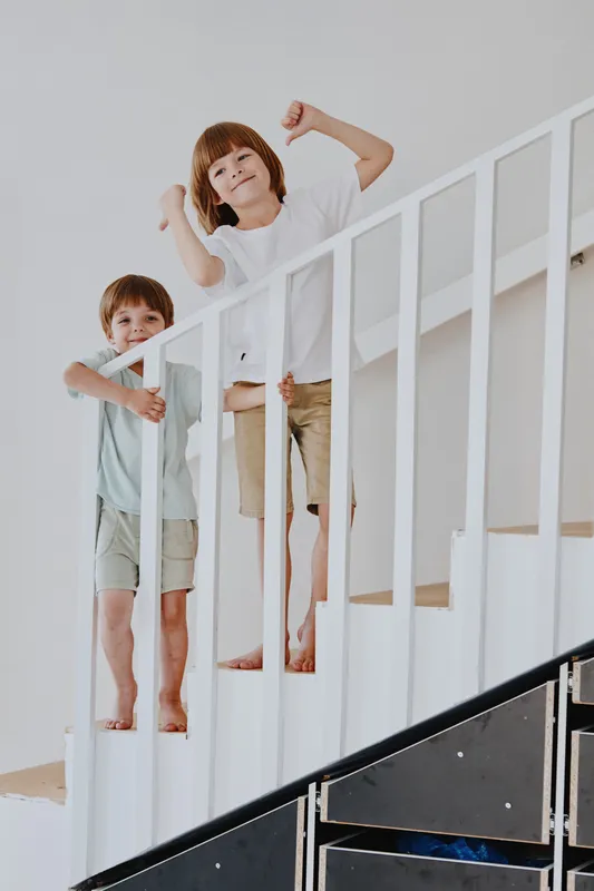 Two cheerful boys playing on the stairs, showcasing joy and energy. Their playful expressions capture the essence of childhood and adventure in a bright environment.