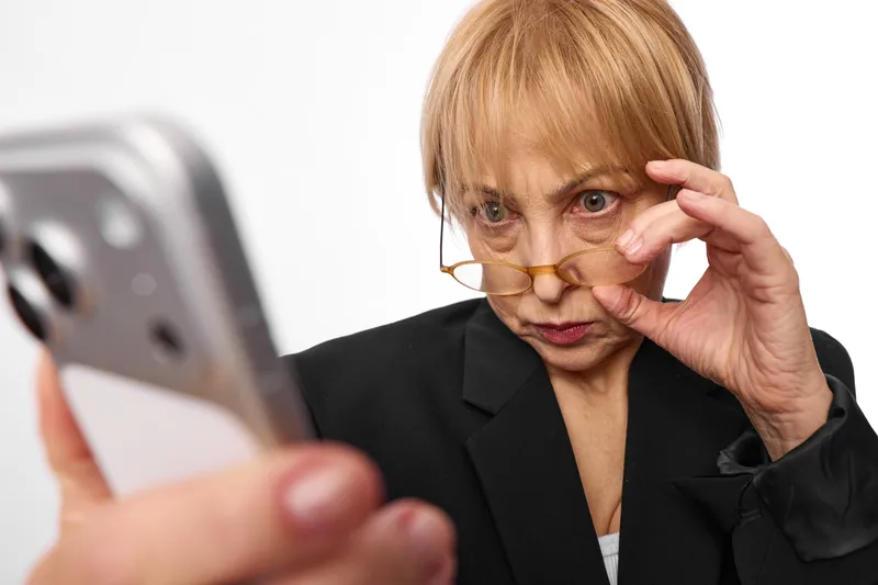 Woman elderly glasses smartphone worry face touch eye communication call, closeup senior portrait, business blazer, hand adjusting glasses, smartphone view, white background