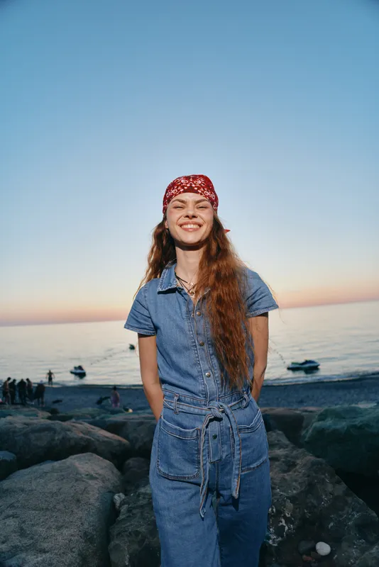 lifestyle woman in modern boho-western denim street style smiling outdoors by the seaside with warm film color and relaxed summer mood