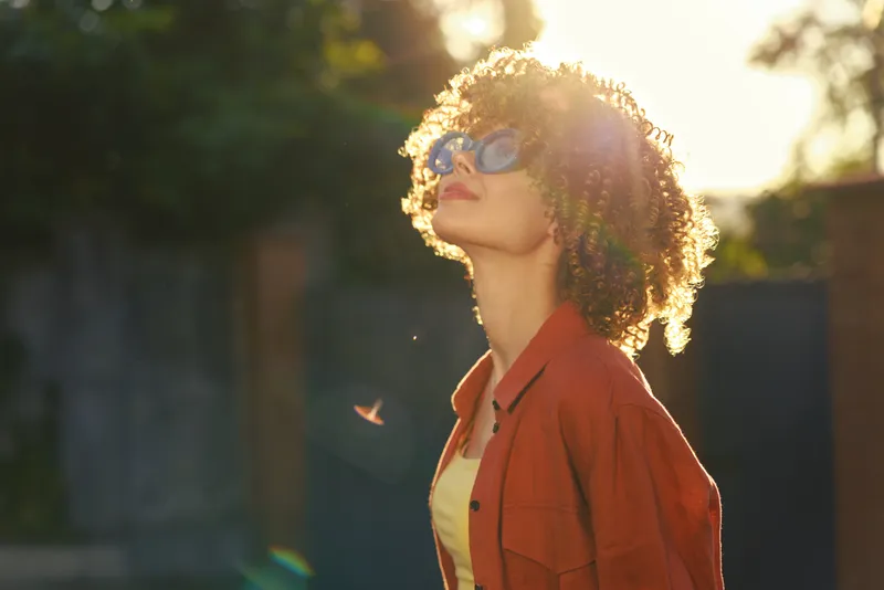 Woman outdoors lifestyle sunlight sunglasses portrait casual fashion relaxed mood cheerful moment natural colors greenery background
