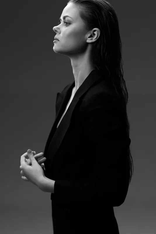 Black and white portrait of a serious woman with wet hair wearing a dark blazer in profile view.