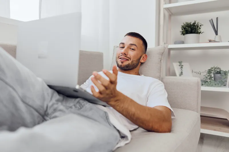 Relaxed man engaging with his laptop, exploring digital detox while balancing work and personal life. Focus on mental health and authentic imperfection.
