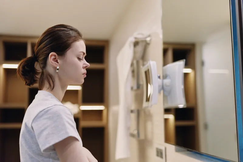 Woman at a self service kiosk, focused on a touchscreen in a modern office lobby, preparing a transaction with monitor, interface and soft lighting