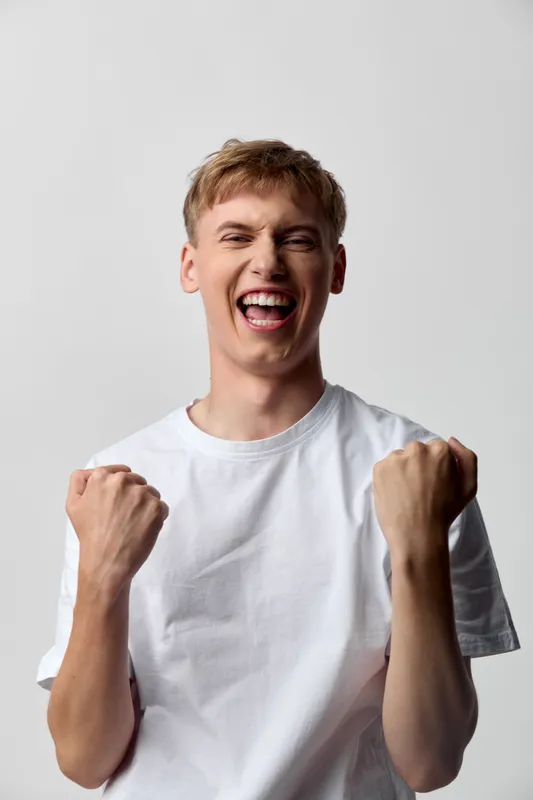 Excited, cheering, celebration, victory, happiness, young, man, expression, emotion, energy, white tee, victory moment, strong pose, celebratory gesture, joyful mood, enthusiasm, upbeat, personal