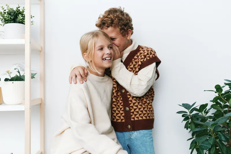 Authentic moment of playful siblings sharing a warm indoor scene in cozy attire, celebrating life with laughter, care, and candid connection that feels natural, loving, and refreshingly real.