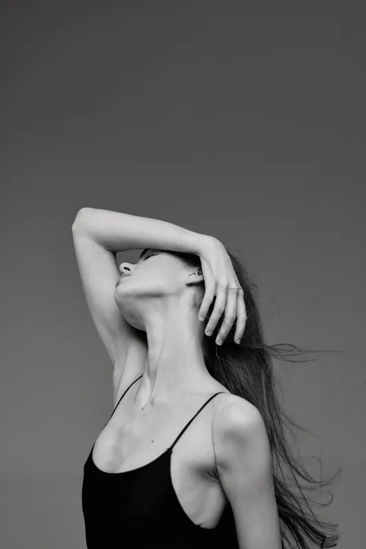 black and white woman posing with arm raised in minimalist style with soft lighting