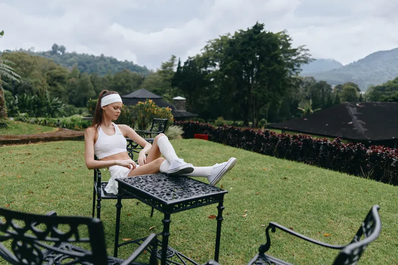 Young athletic model in sporty outfit relaxing outdoors on a sunny day, embodying fitness and well being in a lush garden setting