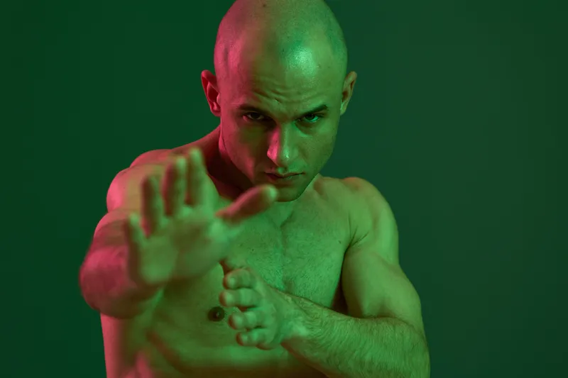 Intense man posing in dramatic light, showcasing strength and determination. This black and white image captures a powerful moment of focus and energy.
