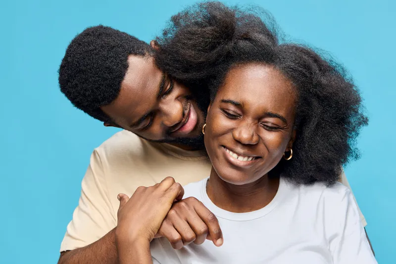 Happy couple embracing on a blue background, showcasing love and joy, perfect for representing romance, relationships, and happiness in photography