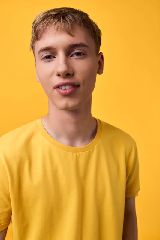 Young man in a yellow shirt against a bright yellow backdrop, casual studio shot highlighting vibrant color and relaxed mood, ideal for fashion, lifestyle, or youth branding