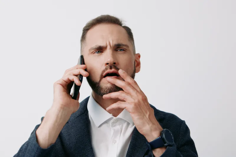 Professional man on an isolated colored background, in business attire, speaking on a phone, showing focus, determination, and a strategic mood.
